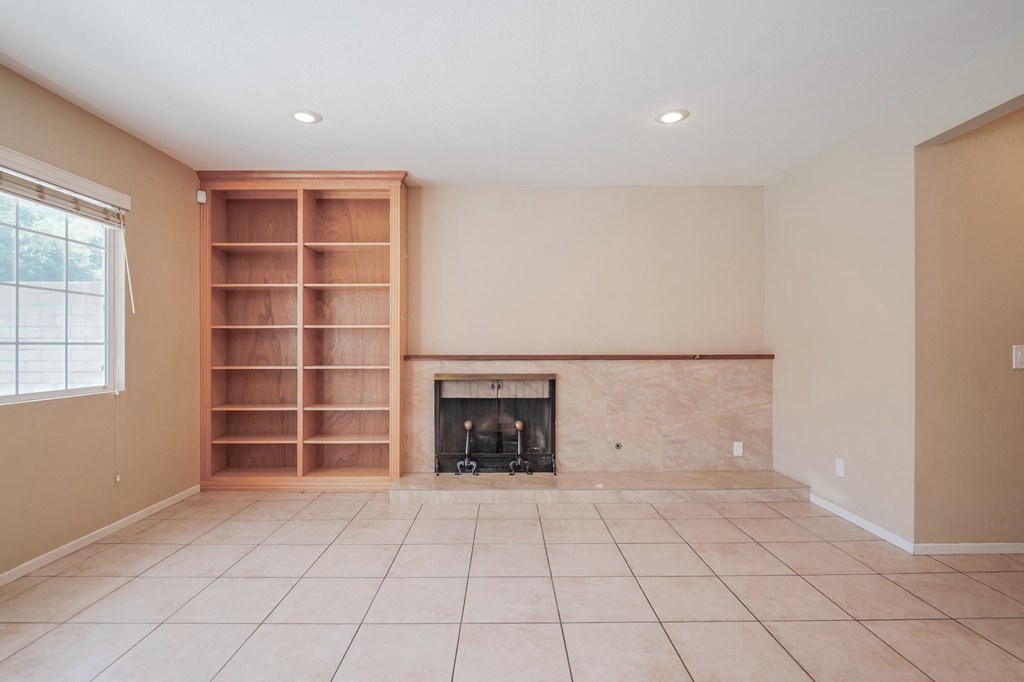 an empty living room with a fireplace and a book shelf