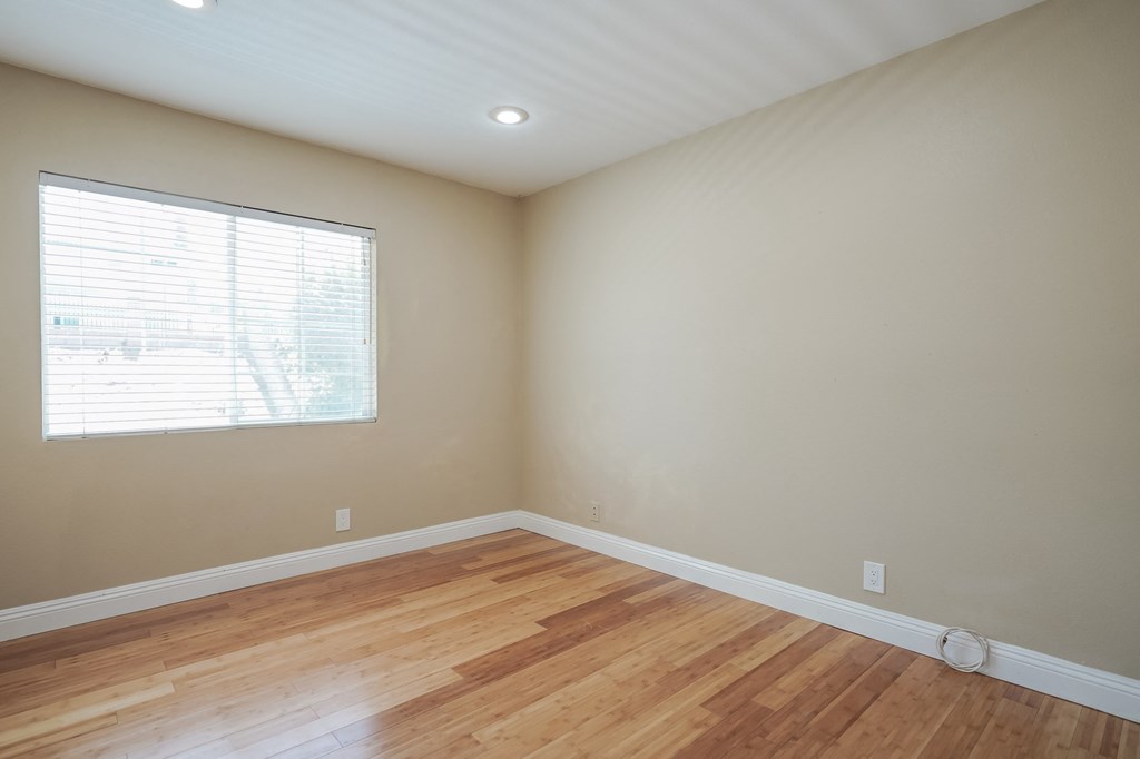 an empty living room with wood floors and a window