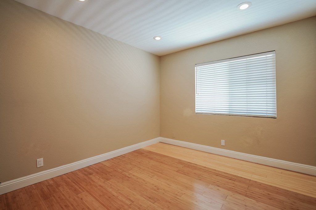 an empty living room with wood floors and a window