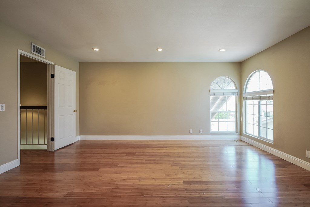 an empty living room with wood floors and a door to a balcony