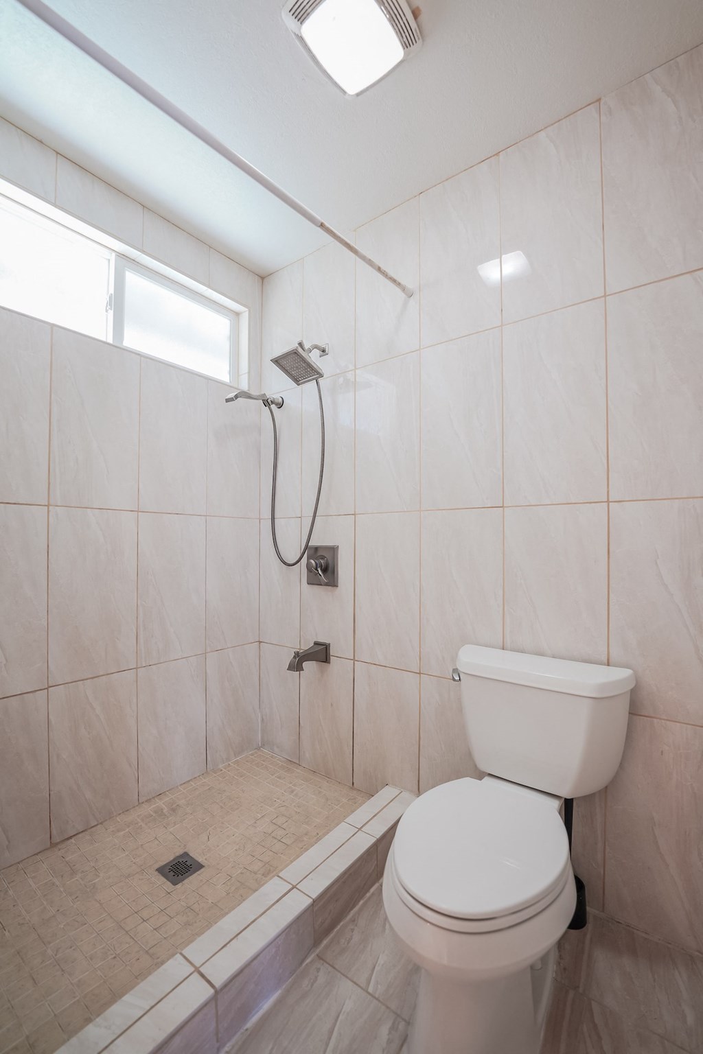 a white bathroom with a toilet and a shower