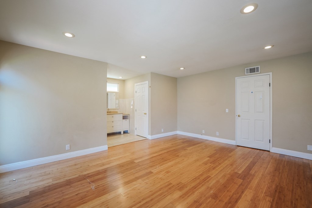 an empty living room with wooden floors and a white door