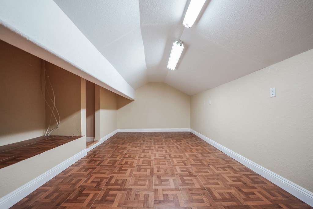 an empty room with wood flooring and a mirrored wall