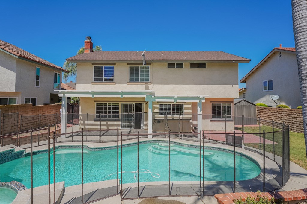 a swimming pool in front of a house with a fence around it