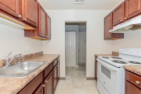 A kitchen with brown cabinets and a white stove top oven.
