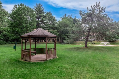 A gazebo sits in the middle of a grassy field.