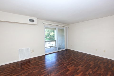 the spacious living room with hardwood flooring and sliding glass doors to a balcony