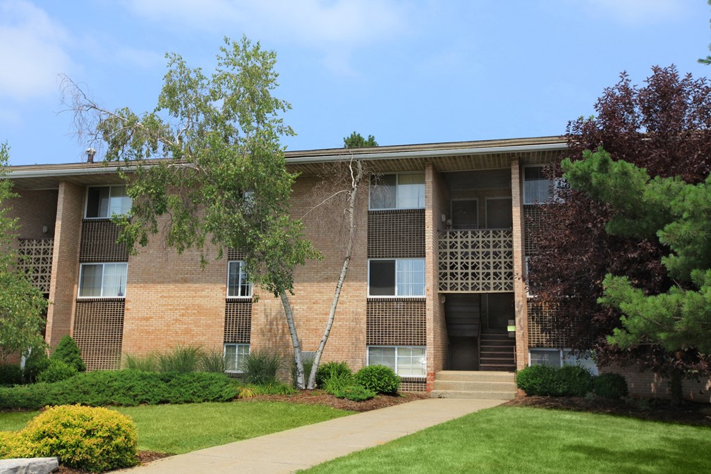 an apartment building with a lawn and trees