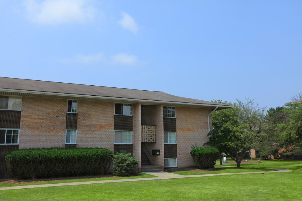 a brick apartment building with a lawn and a blue sky