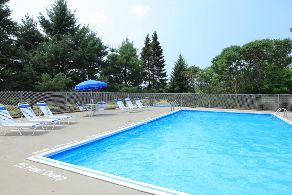 a resort style pool with chairs and an umbrella