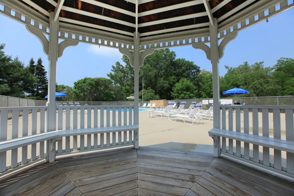 a covered porch with a view of the beach and chairs