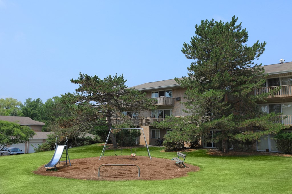 an image of a swing set in front of an apartment building