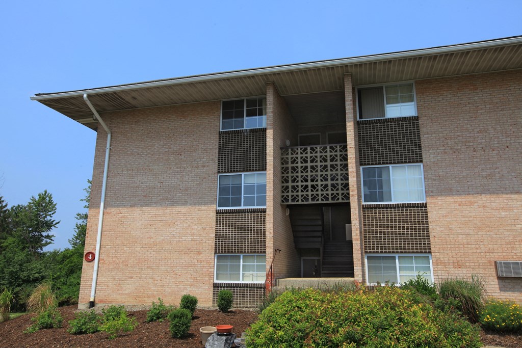 the front of a brick building with a ramp and plants