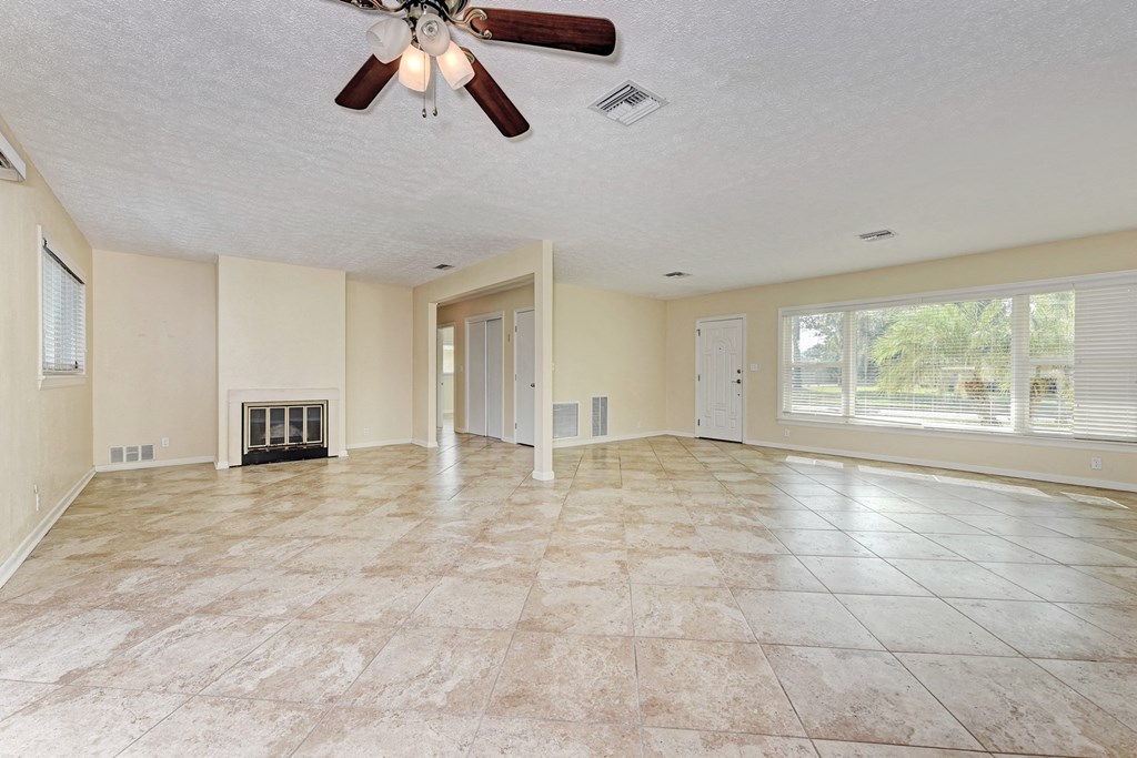 A spacious room with a fireplace and a ceiling fan.