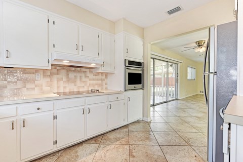 A kitchen with white cabinets and a tiled backsplash.