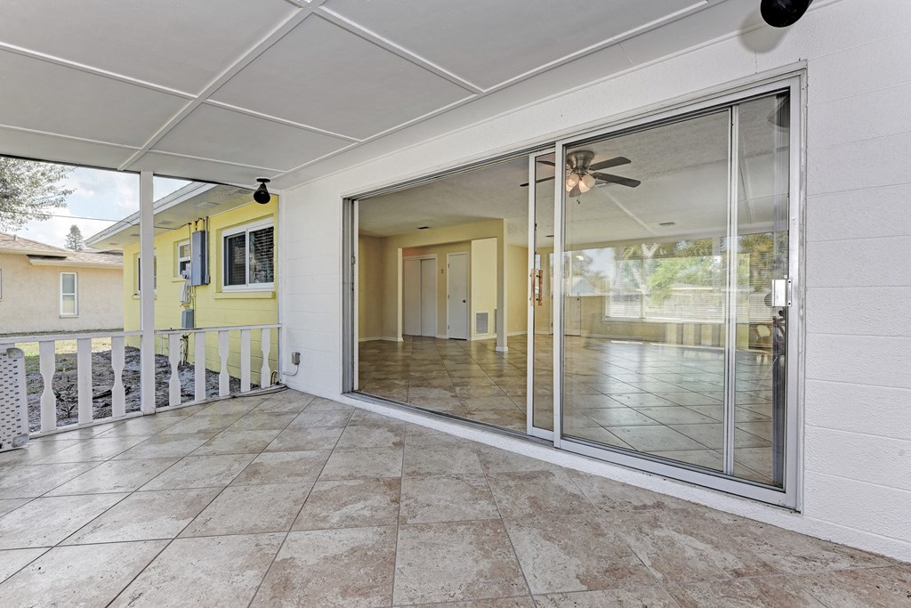 A patio with a sliding glass door and a ceiling fan.