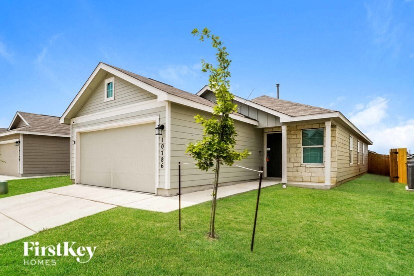 A house with a garage and a tree in front of it.