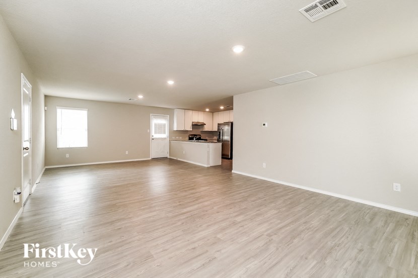 A spacious empty room with wooden flooring and white walls.