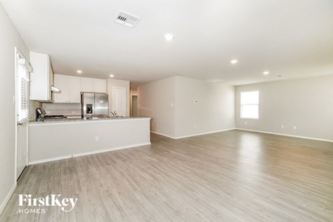 A spacious kitchen with white cabinets and a wooden floor.
