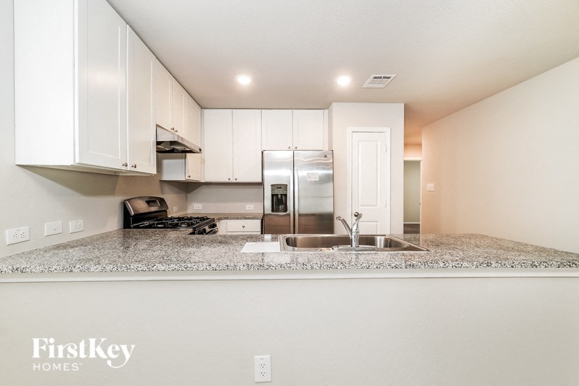 A kitchen with granite countertops and white cabinets.