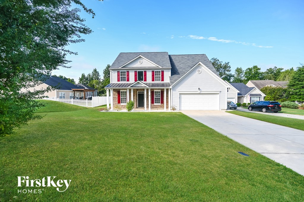 a white house with red shutters and a lawn