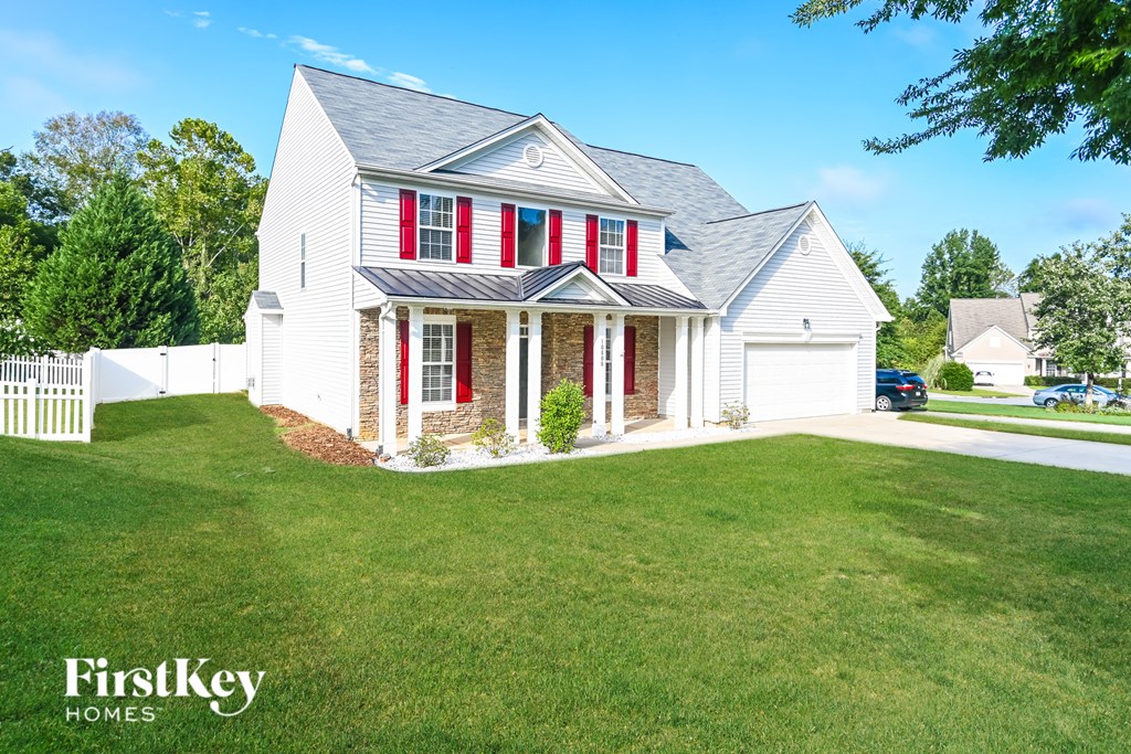 a white house with red shutters and a lawn