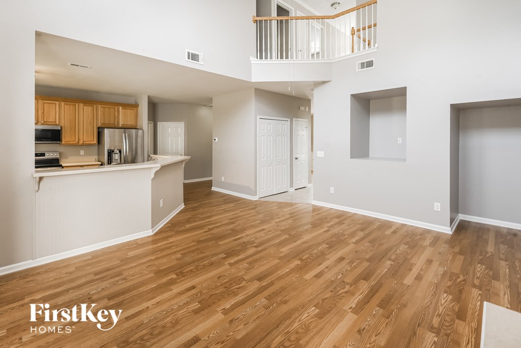 an empty living room and kitchen with wood flooring