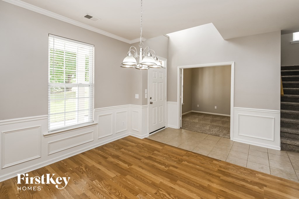 a living room with white walls and wooden floors and a staircase