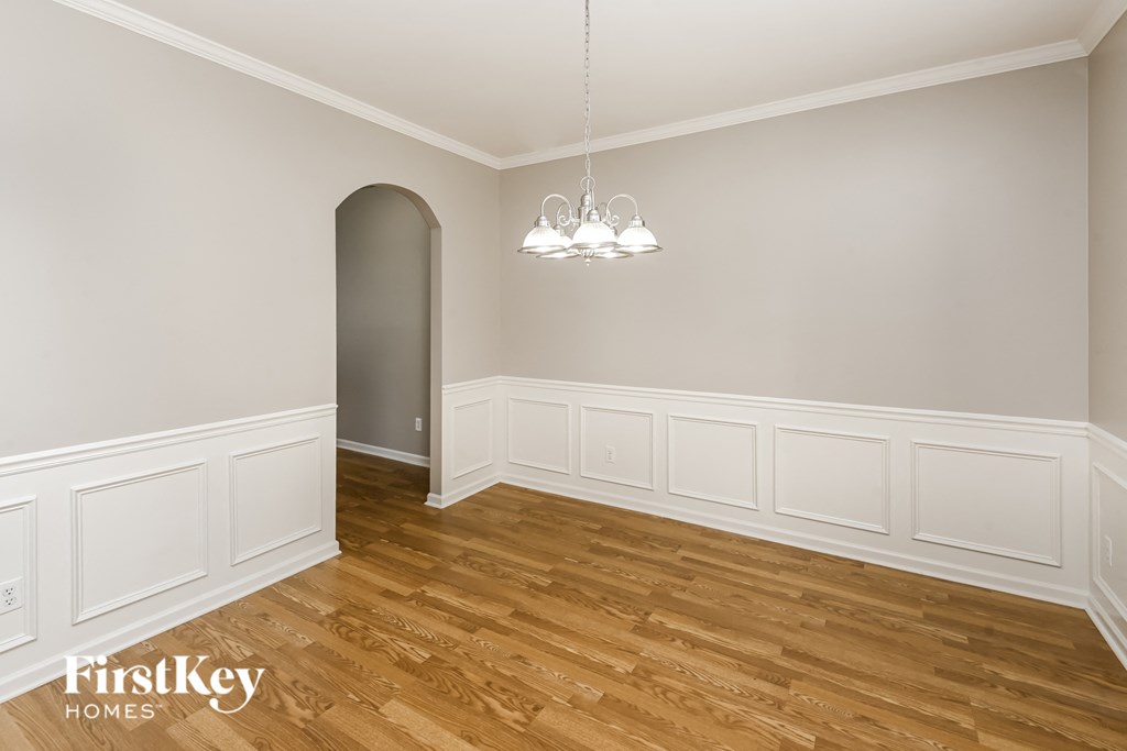 the living room of a house with white walls and wooden floors
