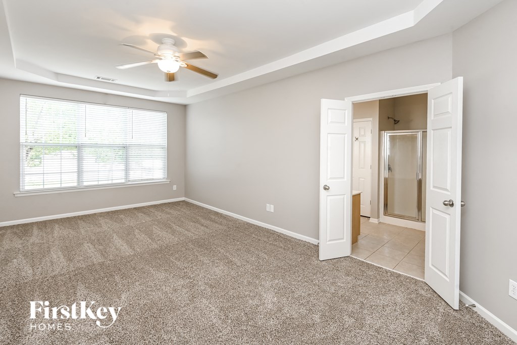 a bedroom with a ceiling fan and a door to a bathroom