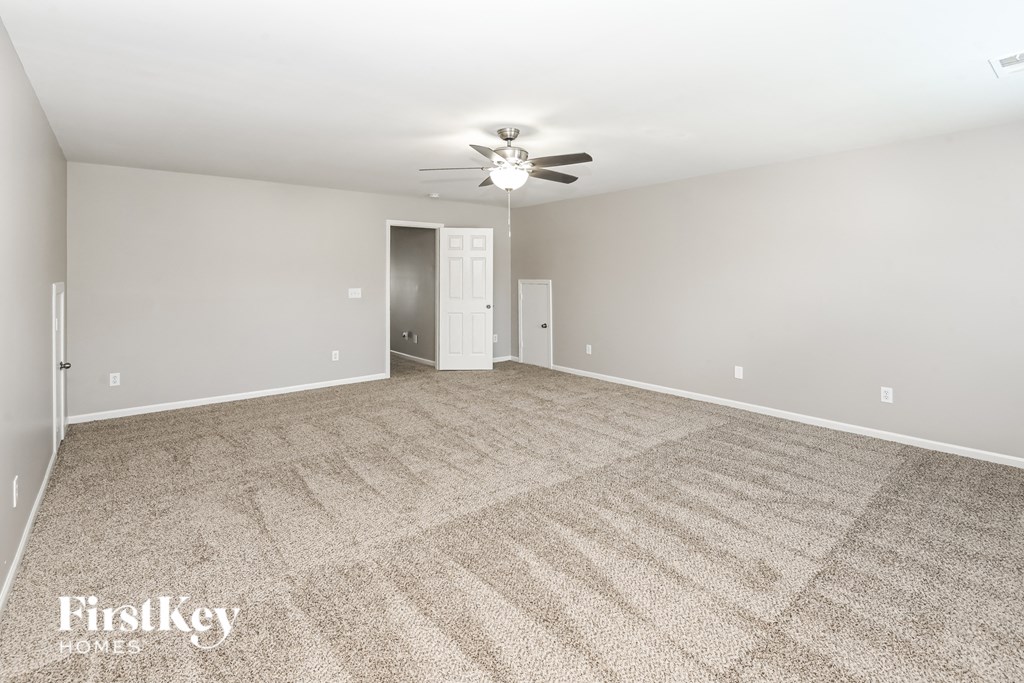 a spacious living room with carpet and a ceiling fan