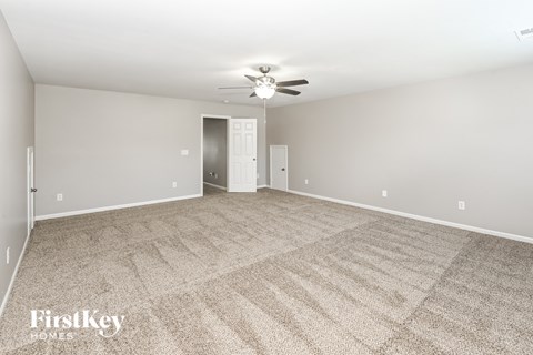 a spacious living room with carpet and a ceiling fan