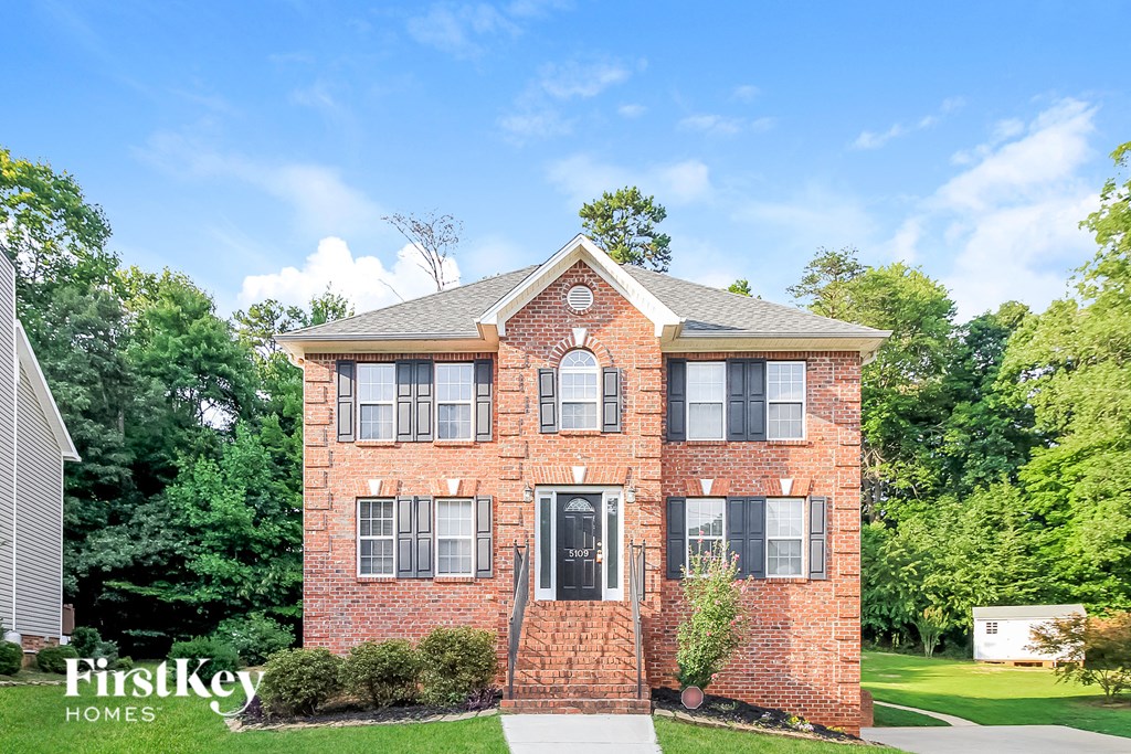A brick house with a black door and windows is for sale.