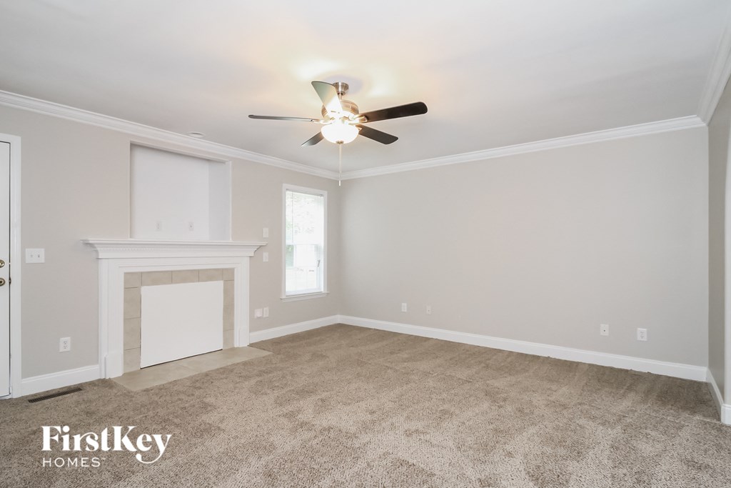 A spacious room with a fireplace and a ceiling fan.