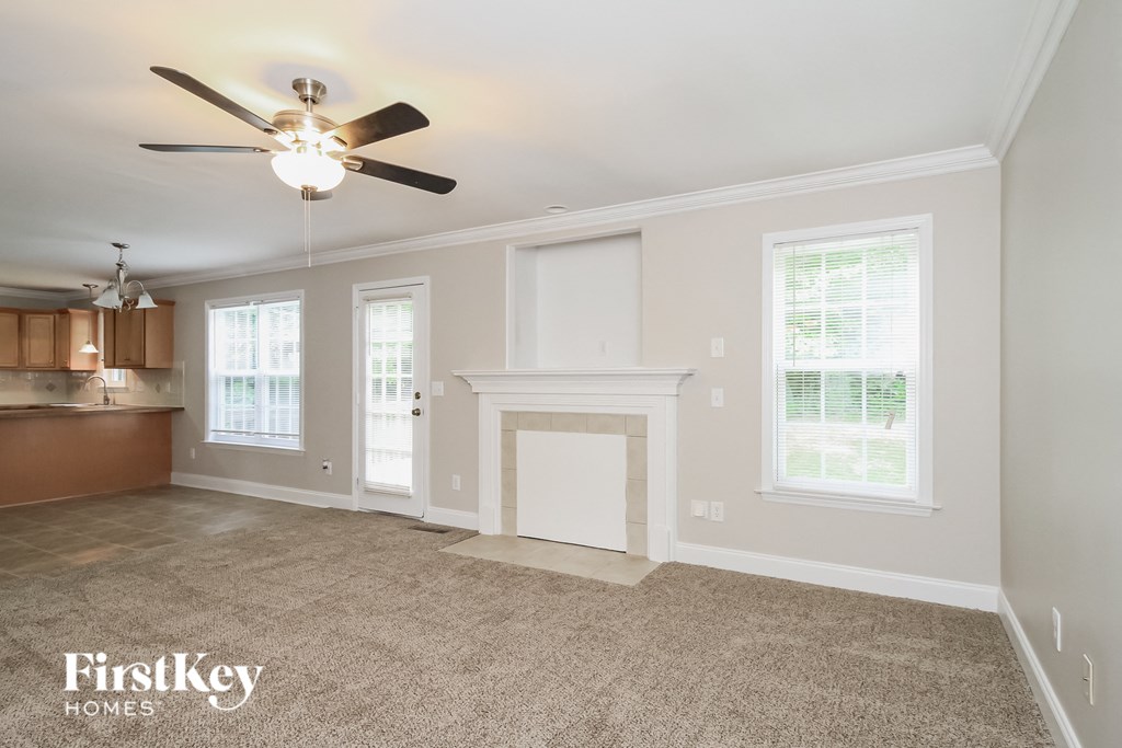 A spacious living room with a fireplace and a ceiling fan.