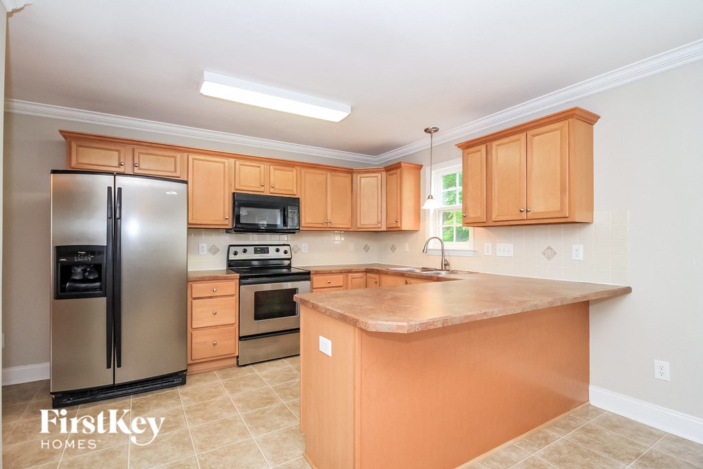 A kitchen with a refrigerator, microwave, oven, and sink.