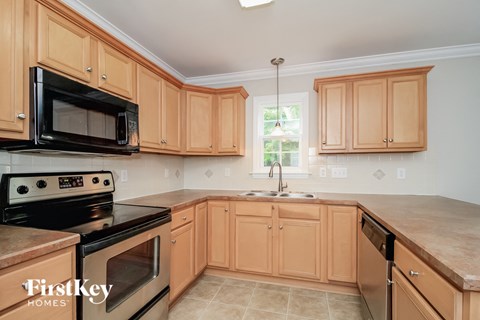 A kitchen with wooden cabinets and a black microwave.