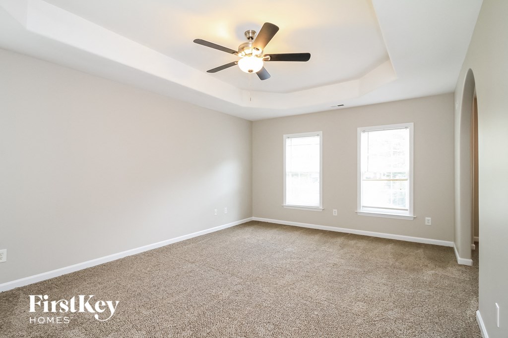 A spacious room with a ceiling fan and carpeted floor.