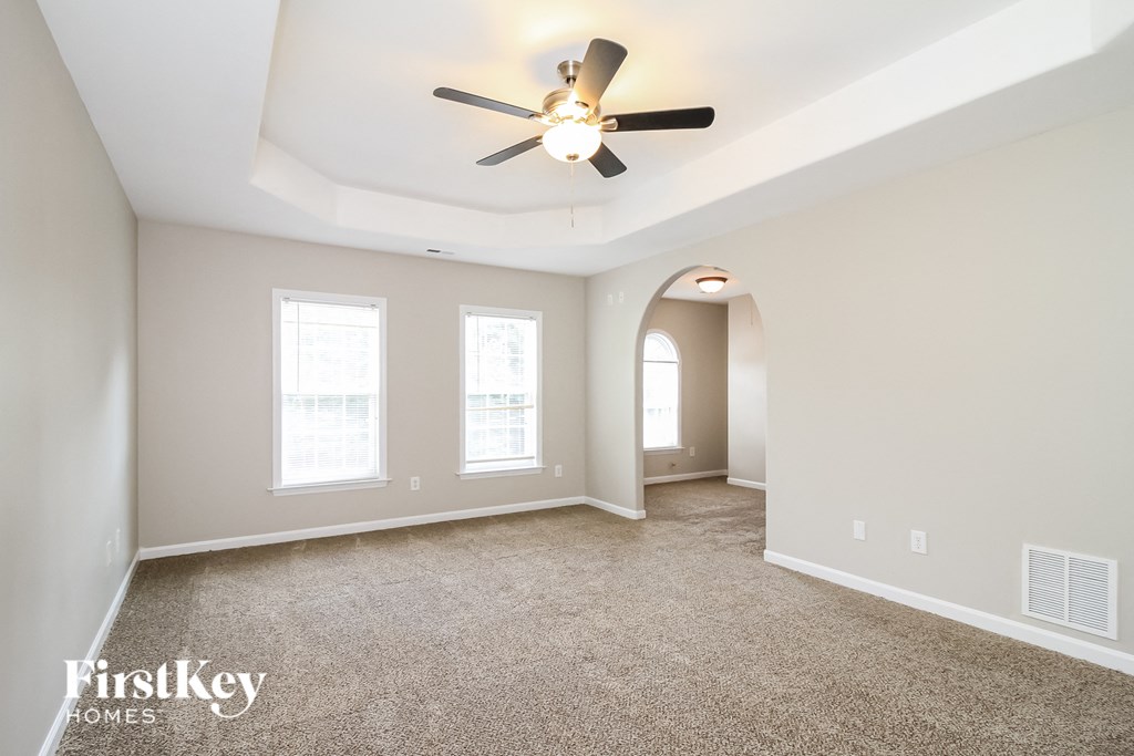 A spacious room with a ceiling fan and carpeted floor.