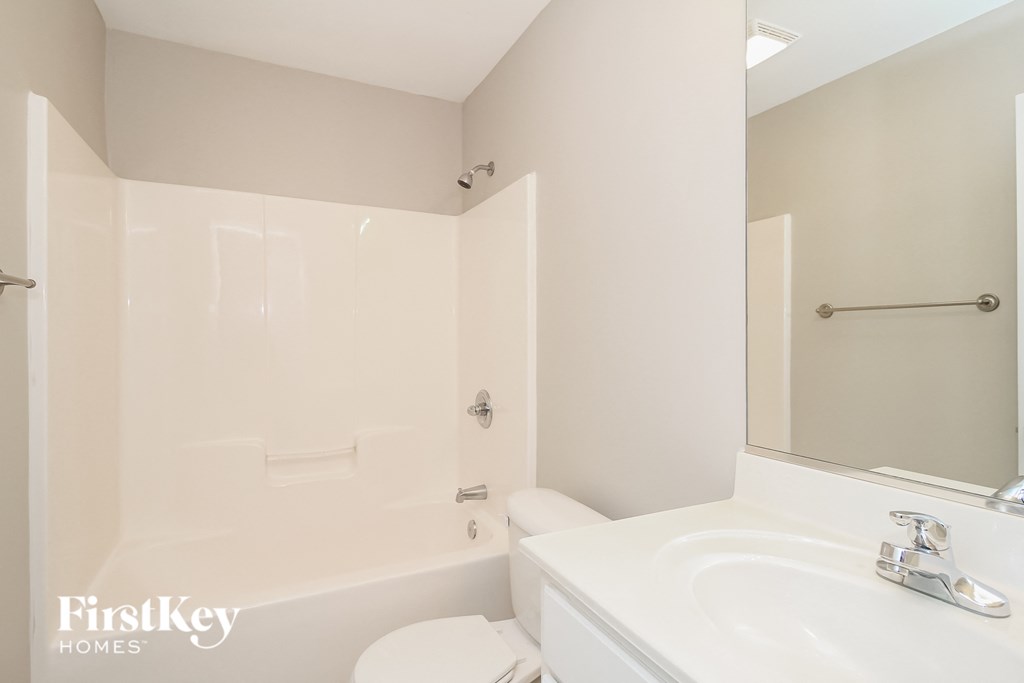 A white bathroom with a tub, toilet, and sink.