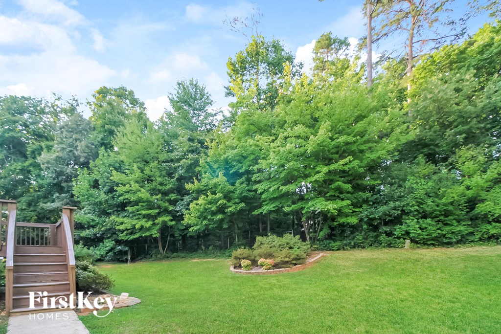 A lush green backyard with a wooden staircase leading to a deck.