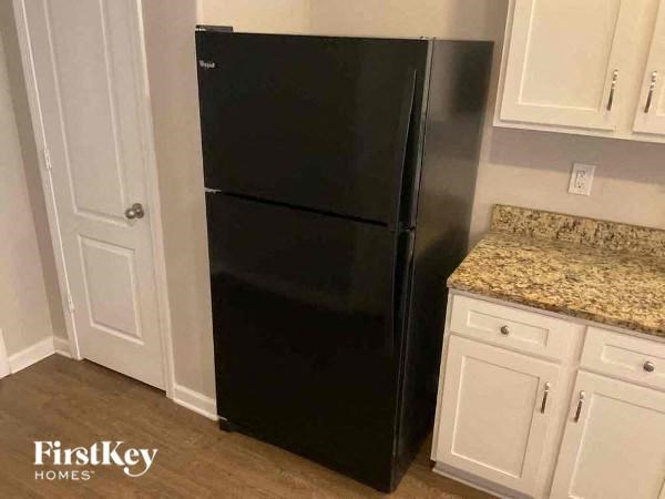a black refrigerator in a kitchen with white cabinets