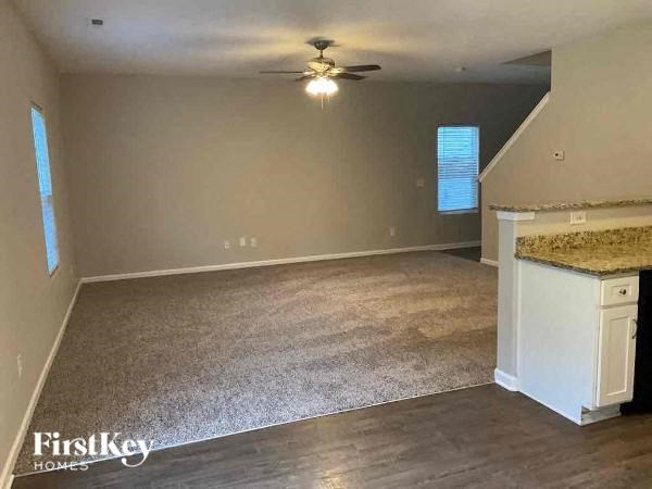 an empty living room with a ceiling fan