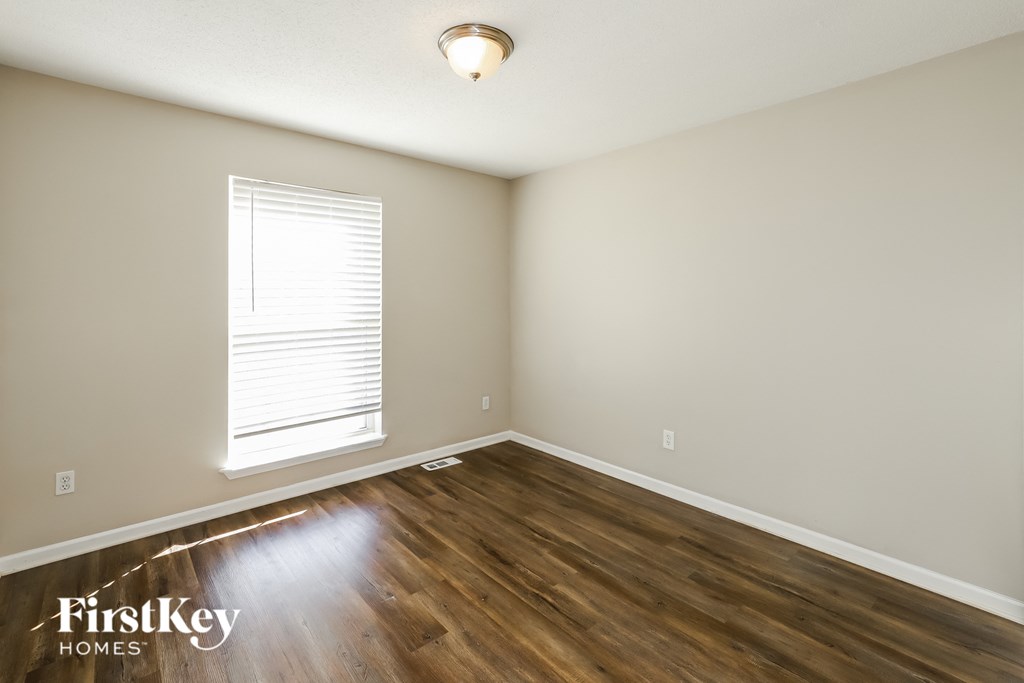 the second bedroom with hardwood flooring and a window