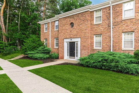 the front of a brick building with a sidewalk and grass