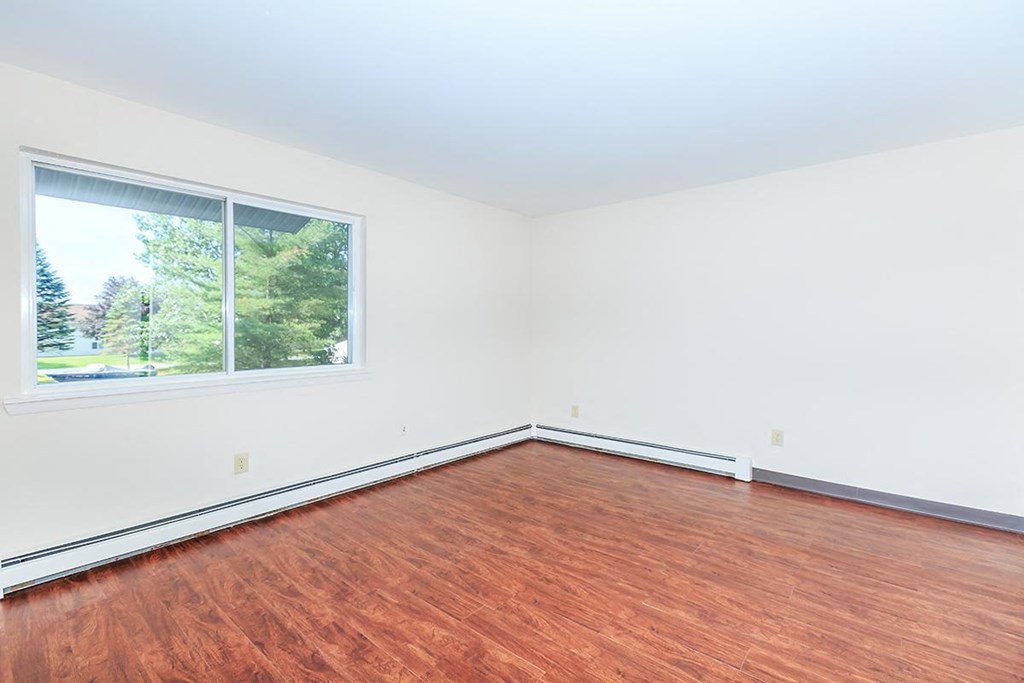an empty room with a large window and wood flooring