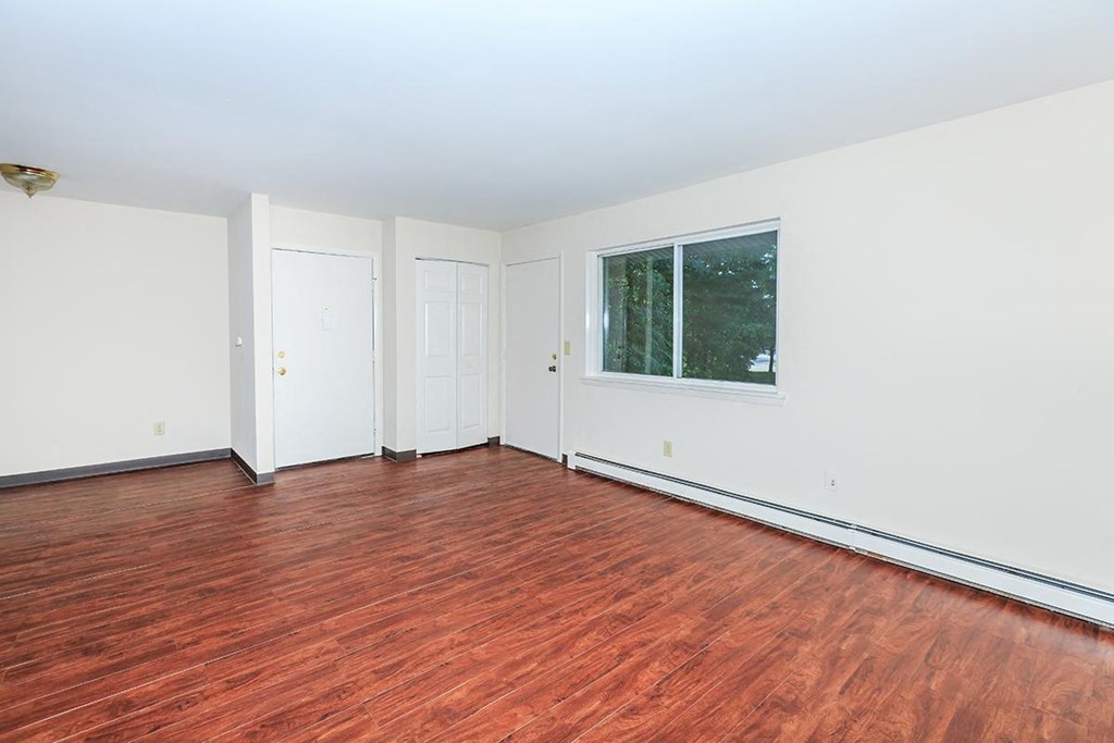 a room with wood floors and white walls and a window