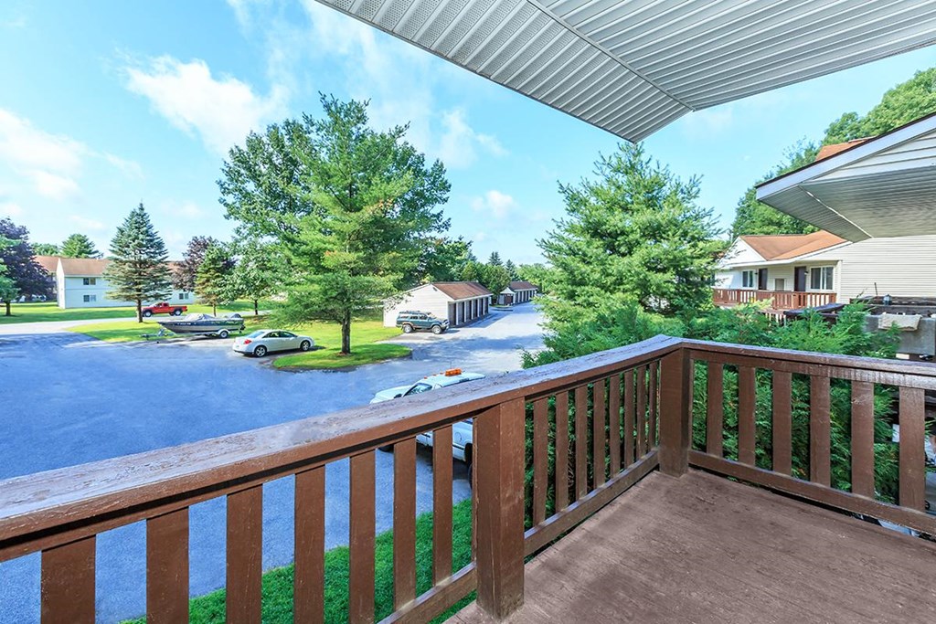 a balcony with a view of a parking lot and trees