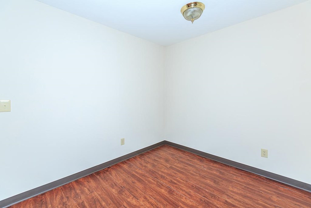 an empty room with wood floors and white walls