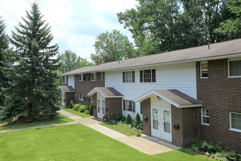 a white and brick house with a yard and a tree